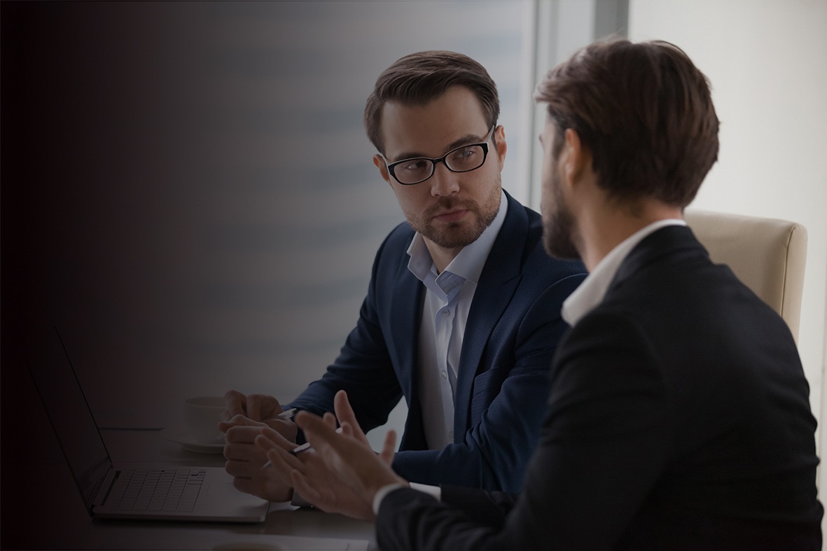 Two businessmen discussing work at laptop